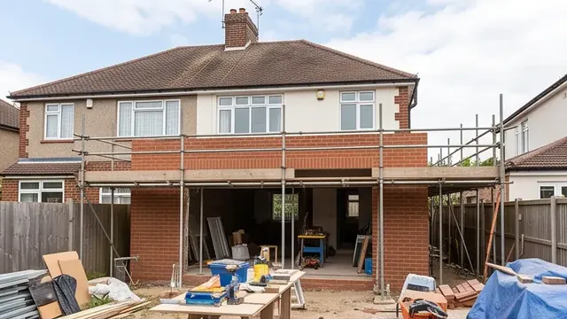 Brick single-storey extension under construction with scaffold at a 1930s semi-detached home