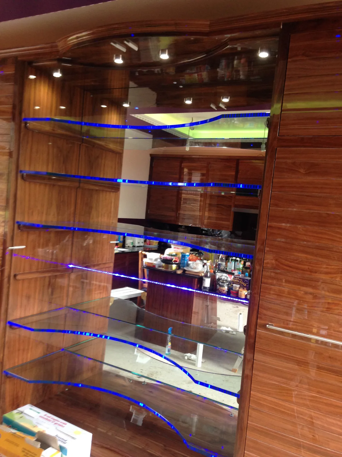 Detail of solid walnut kitchen with curved LED-lit glass display shelving, Sunningdale refurbishment