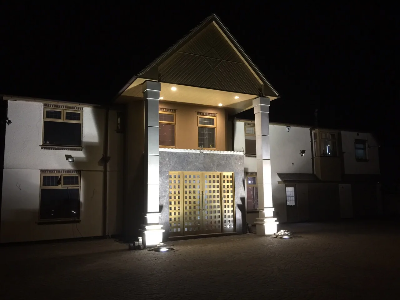 Illuminated granite pillars and marble entrance porch at night after a full Sunningdale refurbishment