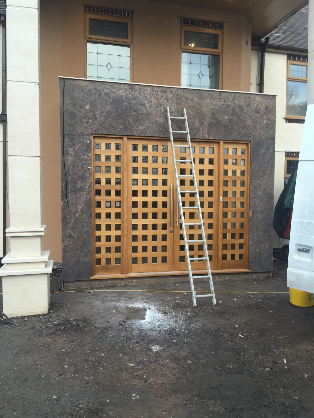 Finished marble-clad porch surround with bespoke oak lattice entrance doors, Sunningdale full refurbishment